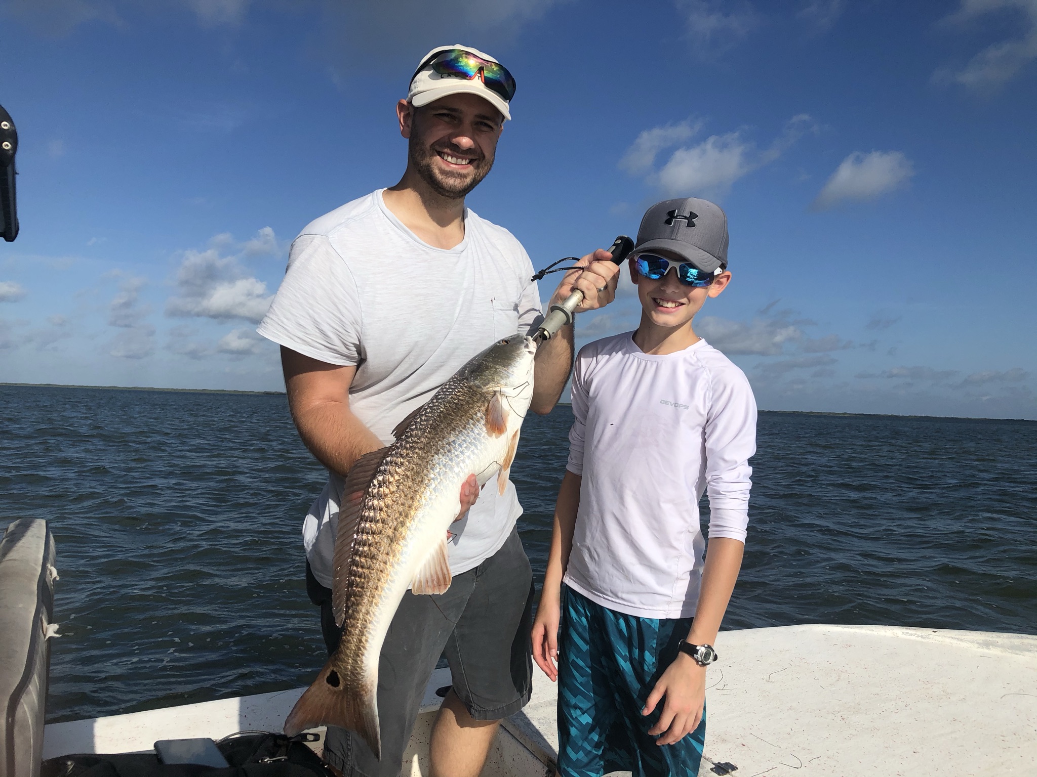 Two anglers showing a redfish aboard the boat